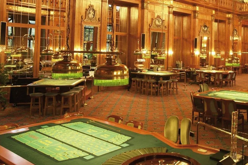 Klassischer Spielsaal im Casino Wiesbaden mit Roulette-Tischen, grünem Filz und Kronleuchtern unter einer verzierten Holzdecke
