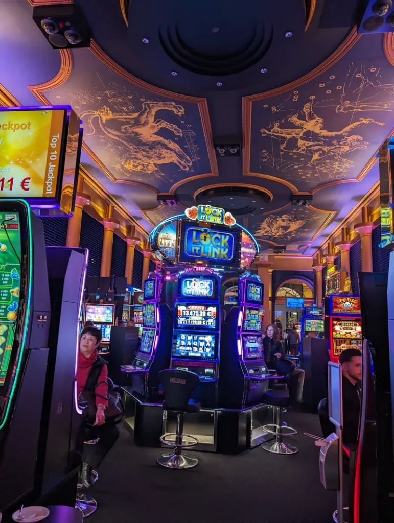 Moderner Automatensaal im Casino Wiesbaden mit leuchtenden Slot-Maschinen und einer künstlerisch gestalteten Decke