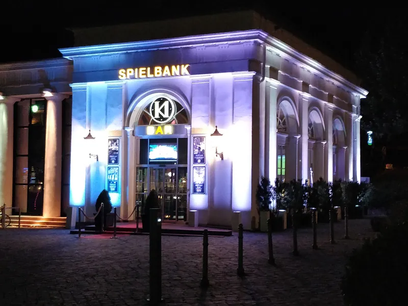 Nachtansicht des beleuchteten Spielbank-Gebäudes im Kurhaus Wiesbaden mit dem „Bar“-Schild und dem Eingangsbereich