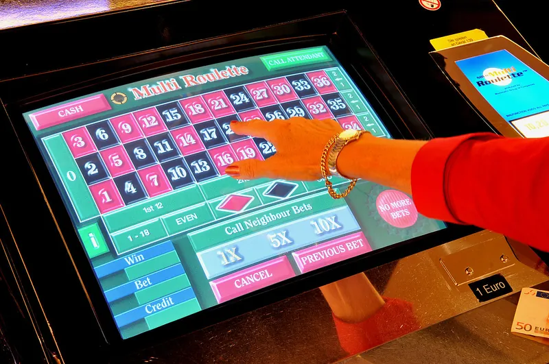 Eine Hand tippt auf den Bildschirm eines elektronischen Multi-Roulette-Terminals im Ring Casino